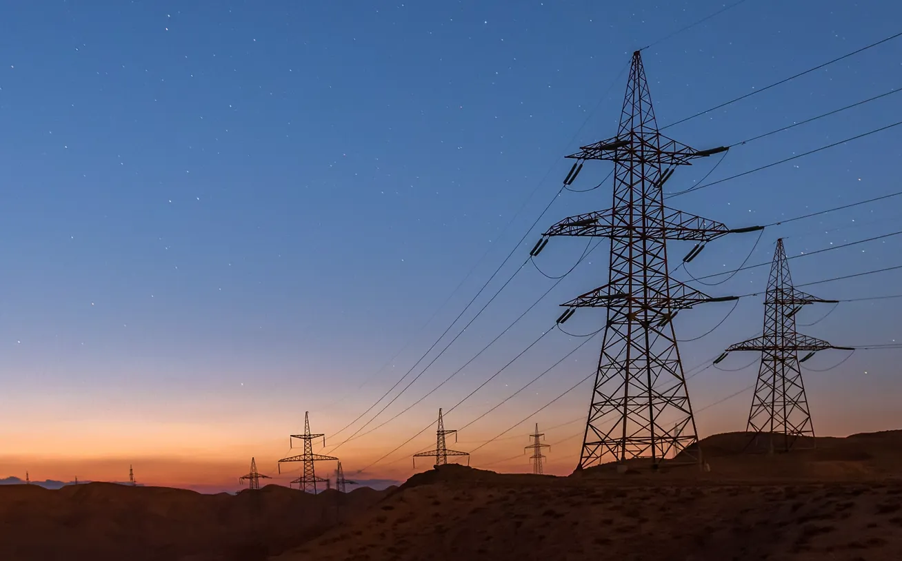 A series high-voltage electric power transmission towers on a rural landscape.